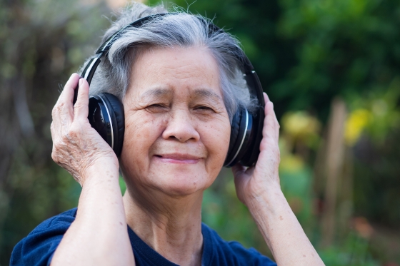 Older woman listening to music through headphones and smiling
