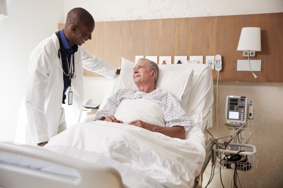Older man in hospital bed speaking with doctor